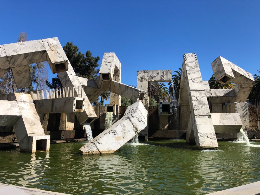 A view of SF's Vallaincourt Fountain show a pile of geometric concrete shapes appear as if they are collapsing into a pool of water