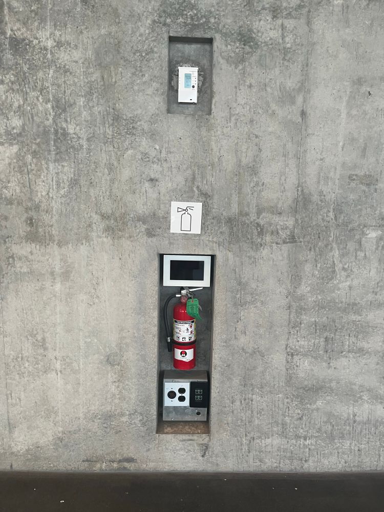 A fir extinguisher embedded in a concrete wall.