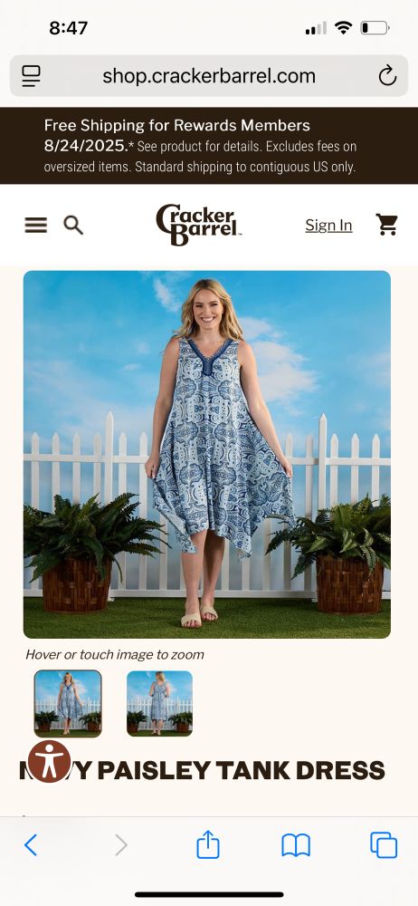 A woman shows off a blue paisley tank dress on a set staged to resemble a garden.