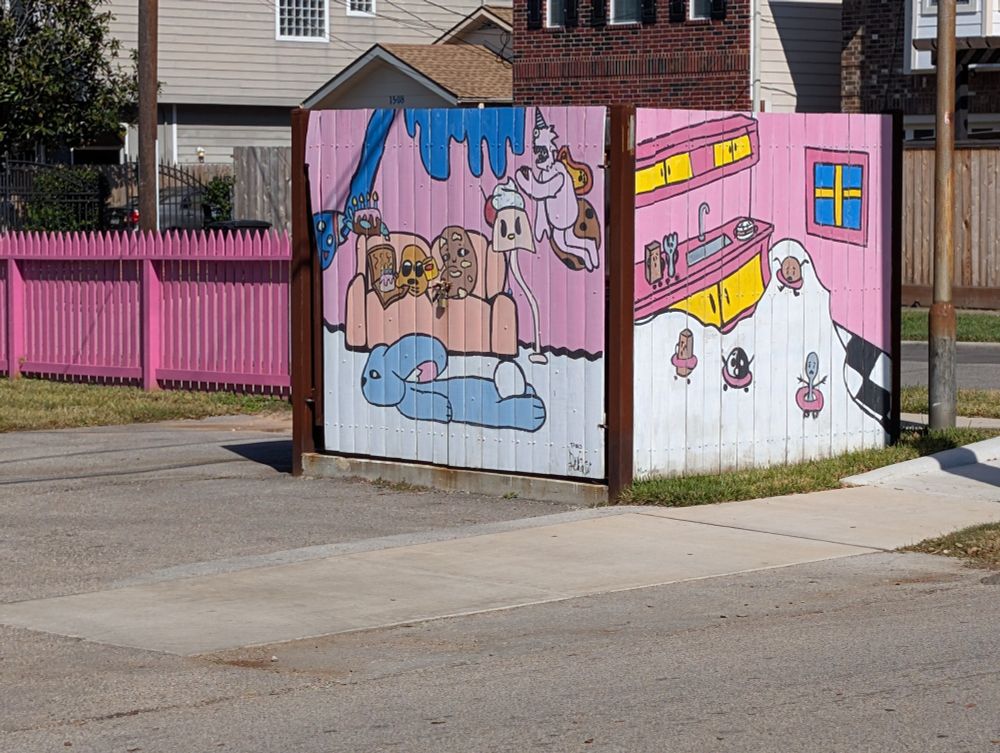 Mural on fence hiding dumpsters 