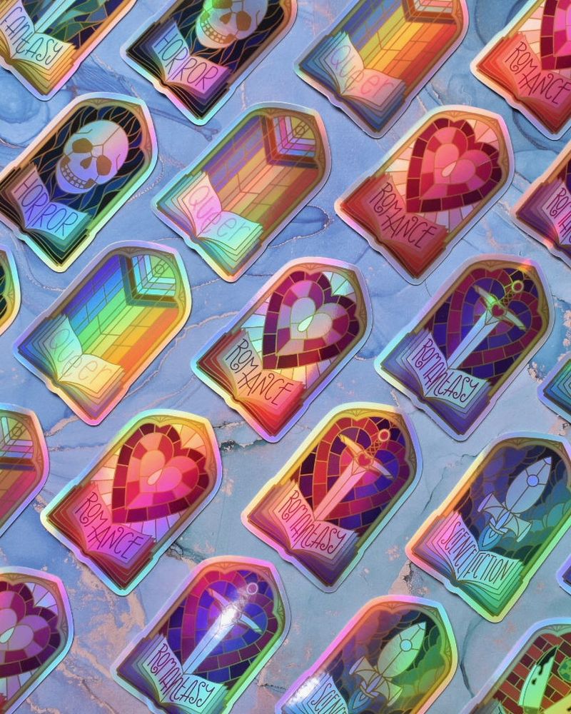 Lines of shiny holographic stickers at an angle going from bottom left up towards top right. Each sticker is in the shape of a traditional stained glass window, with an open book at the bottom. Each line has a different book genre theme with grey/silver oulines. Left to right: Horror, queer, romance, Romantasy, science fiction.