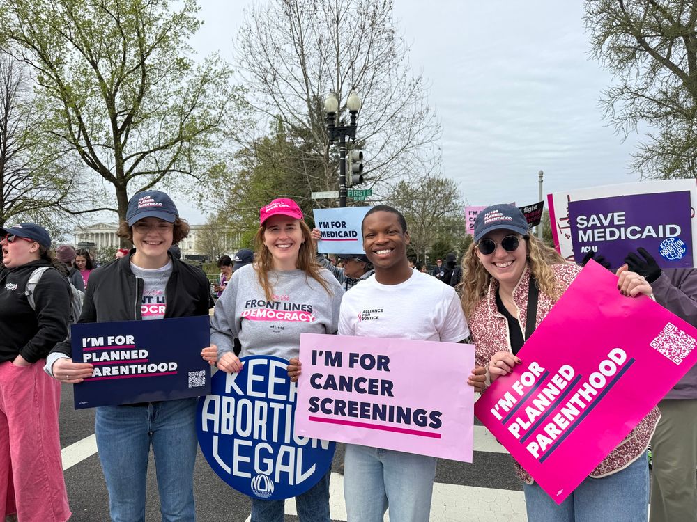 Four people with signs at Planned Parenthood rally outside SCOTUS. 