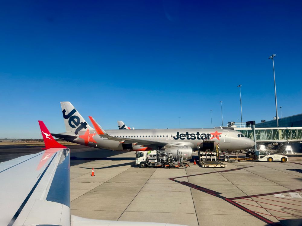 View from a Qantas flight in Adelaide. A Jetstar plane can be seen at the next gate. The sky is purest blue. 