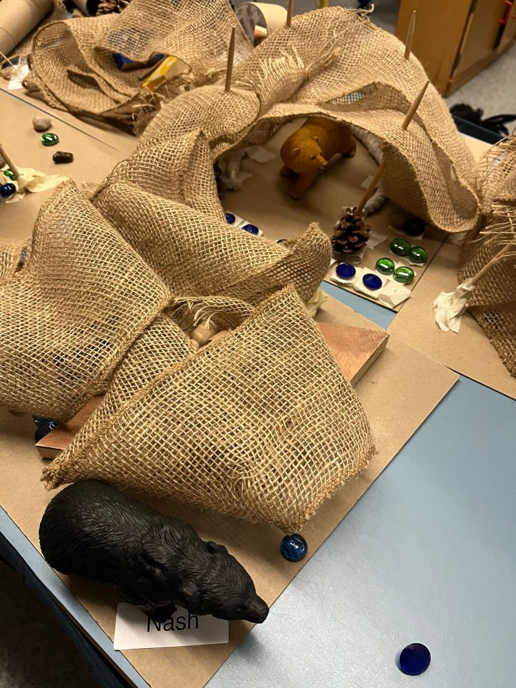 A second picture of some bear dens that the kindergarten class next-door made with the loose parts cart.

If possible, will sometimes leave the kids scenes put together off to the side, somewhere to come back to on another day for further reflection and storytelling. Other times if things need to be cleaned up at the end of a session, we take photos of the scenes so they can be put on screen or print it out later for further work.