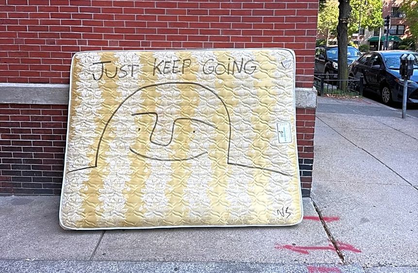 Street mattress inscribed with happy face and slogan: Just keep going