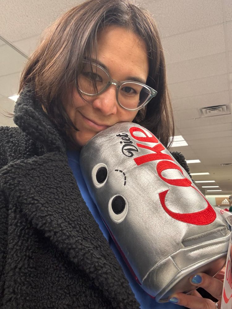 Woman with dark hair and fleece coat holding a stuffed Diet Coke can