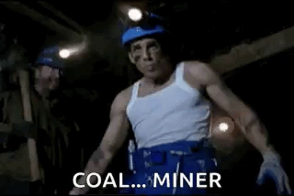 a man in a white tank top and blue pants is standing in a dark room and saying coal miner .