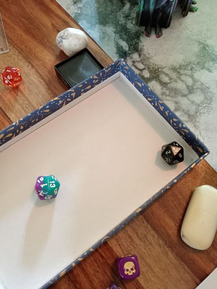 two d20 dice in a tray, one depicting a natural 1, the other a natural 20