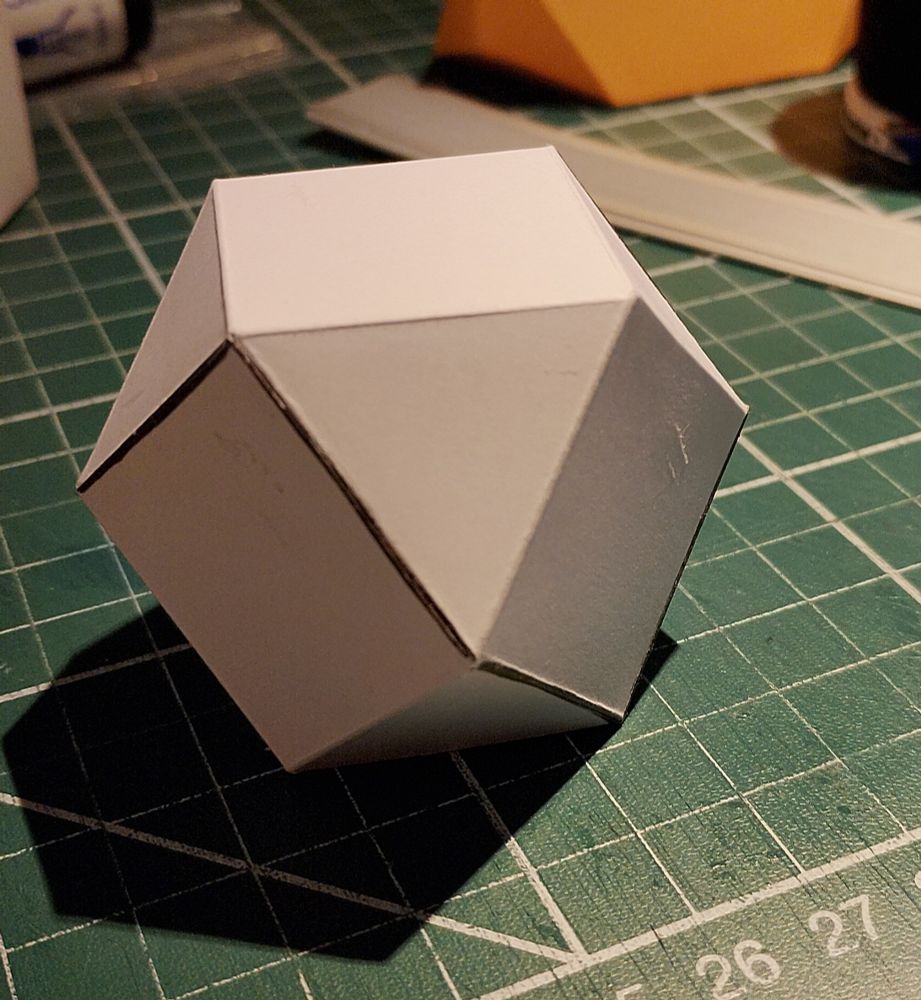 White cardboard representation of a cuboctahedron on a green cutting board.