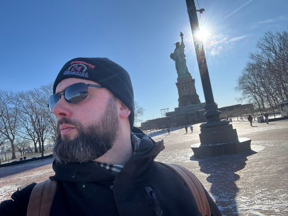 Handsome man with sunglasses near the Statue of Liberty.