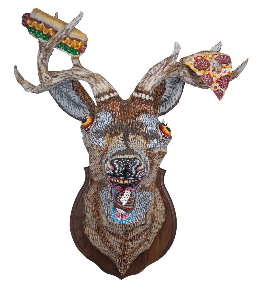 Deer head sculpture with a hot dog and pizza slice in its antlers and a hostess cupcake in its mouth 