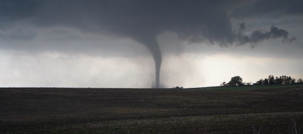 A backlit tornado across a green field