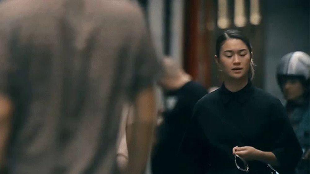 a woman in a black shirt is walking down the street