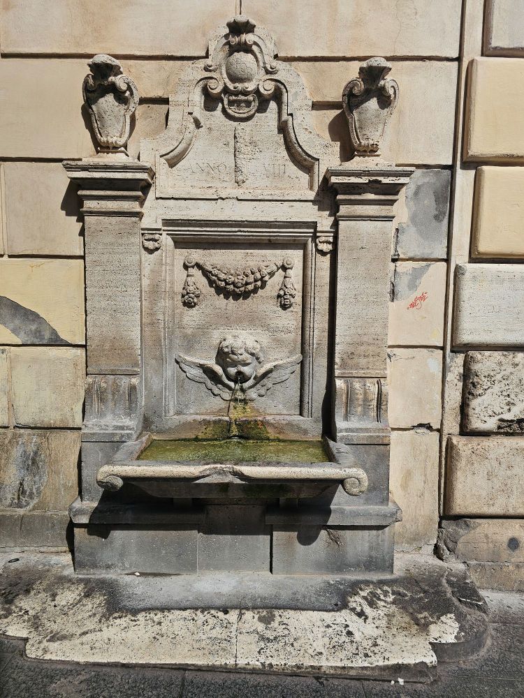 Fountain in stone with drining water attached to the wall
