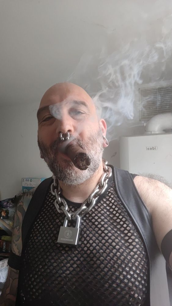 Guy smoking a cigar with large padlocked chain around neck.