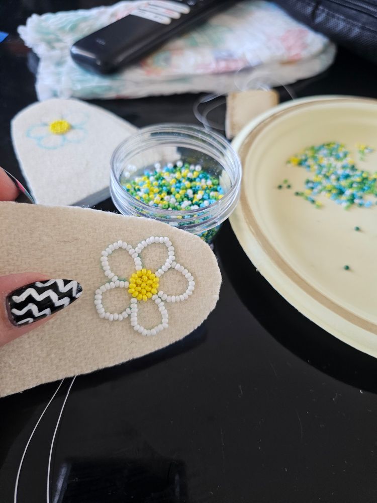 A daisy outline with white beads and yellow beads in the center.