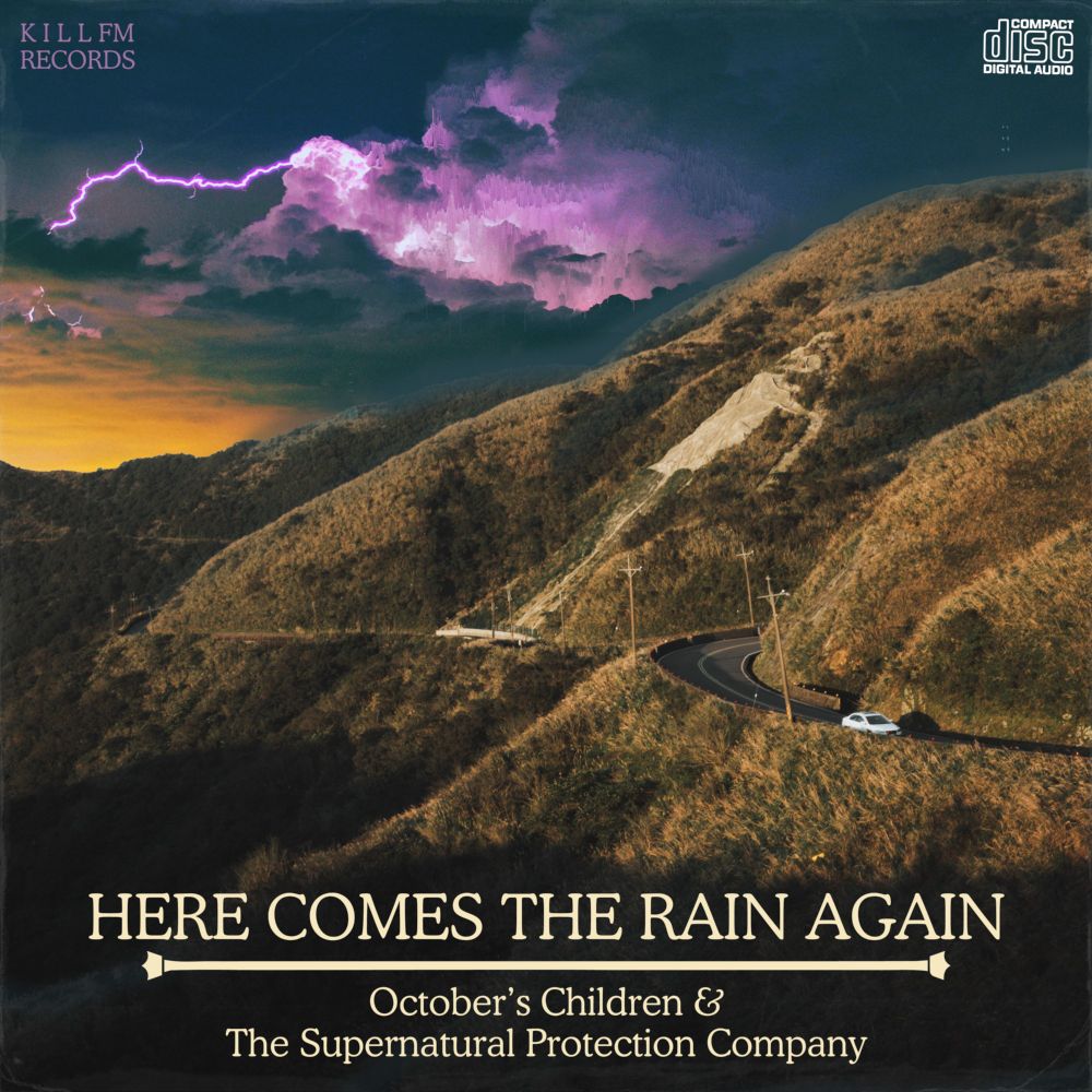 A square image made to look like an album cover.  The photograph is of a single white car driving through browning hills on a winding road, an unnatural purple storm in the distance behind them.  In the upper left corner in a purple text matching the storm are the words "K I L L FM RECORDS".  In the upper right corner is a white version of the "compact disc digital audio" logo.  At the bottom in large capital serif font is the title "HERE COMES THE RAIN AGAIN", separated with a slightly embellished line from the subtitle "October's Children & The Supernatural Protection Company".