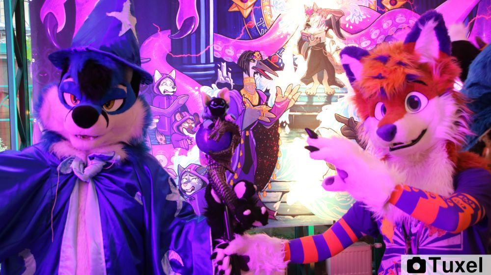 left, a blue fox in a simple magicians/sourceres outfit named Blujay, right a more normal orange fox with blue ears and nose, named Fox Flummox, both holding a Staff with an glas orb on top together. On top of the staff they Summoned a plush Protobean.
