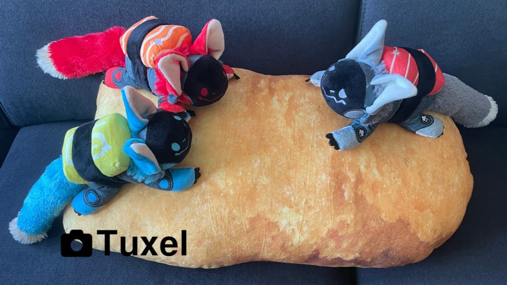 3 protobean plushies sitting on a chicken nugget pillow. The protobeans have sushi like topping (egg, tuna and sake)
