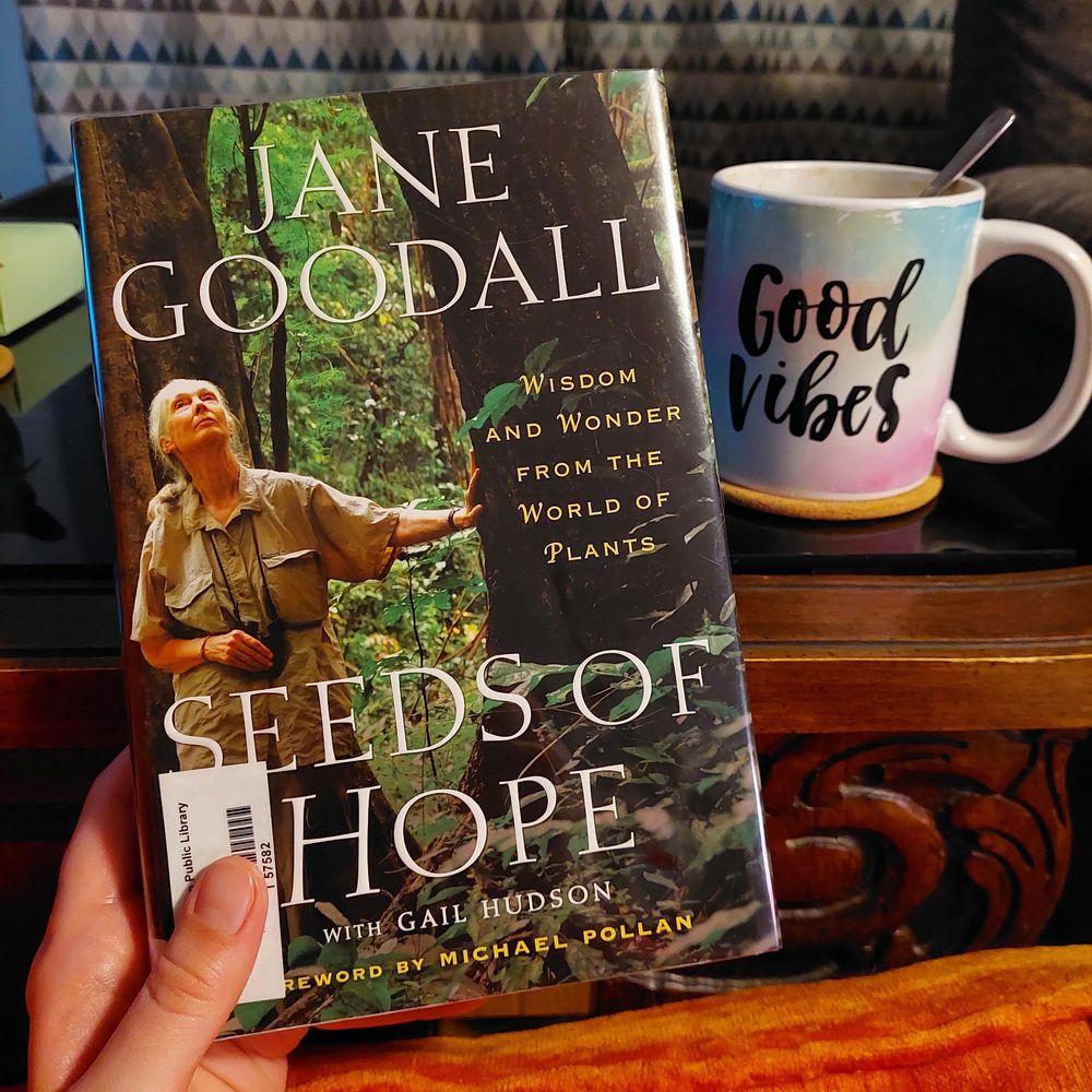 Photo of my hand holding a book titled Seeds of Hope by Jane Goodall.