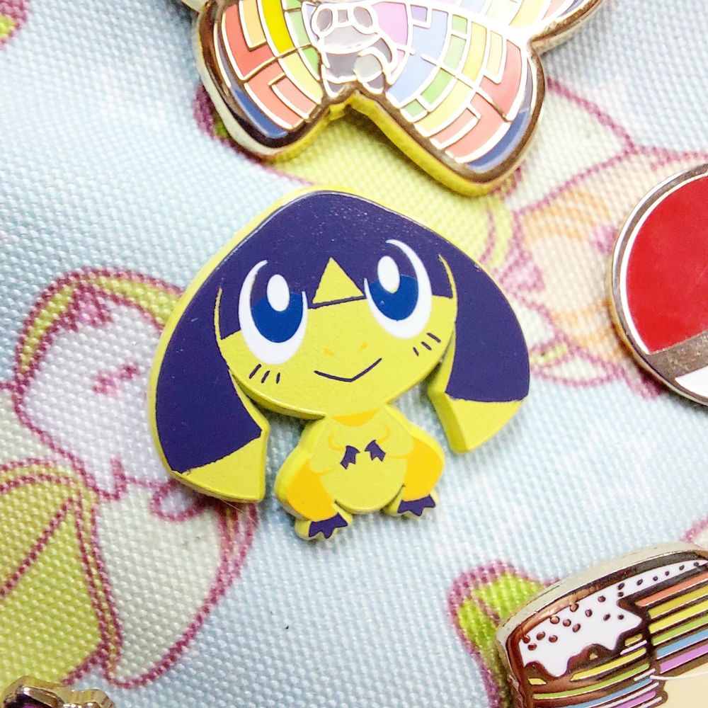 Photo of a Helioptile enamel pin on a bag. Other Pokémon pins are also on the bag.