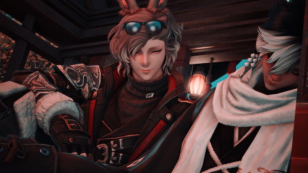 Ren and Akira, two male vieras, sit on the ground beneath the roof of a structure. Ren has fallen asleep while leaning against the wall, and Akira watches him with admiration and a soft smile.