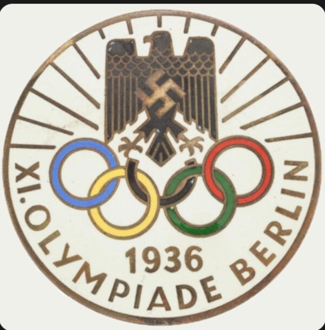 Insignia de las olimpiadas de 1936 en el que se ven los anillos olímpicos bajo el aguila nazi con una esvástica en el pecho. 