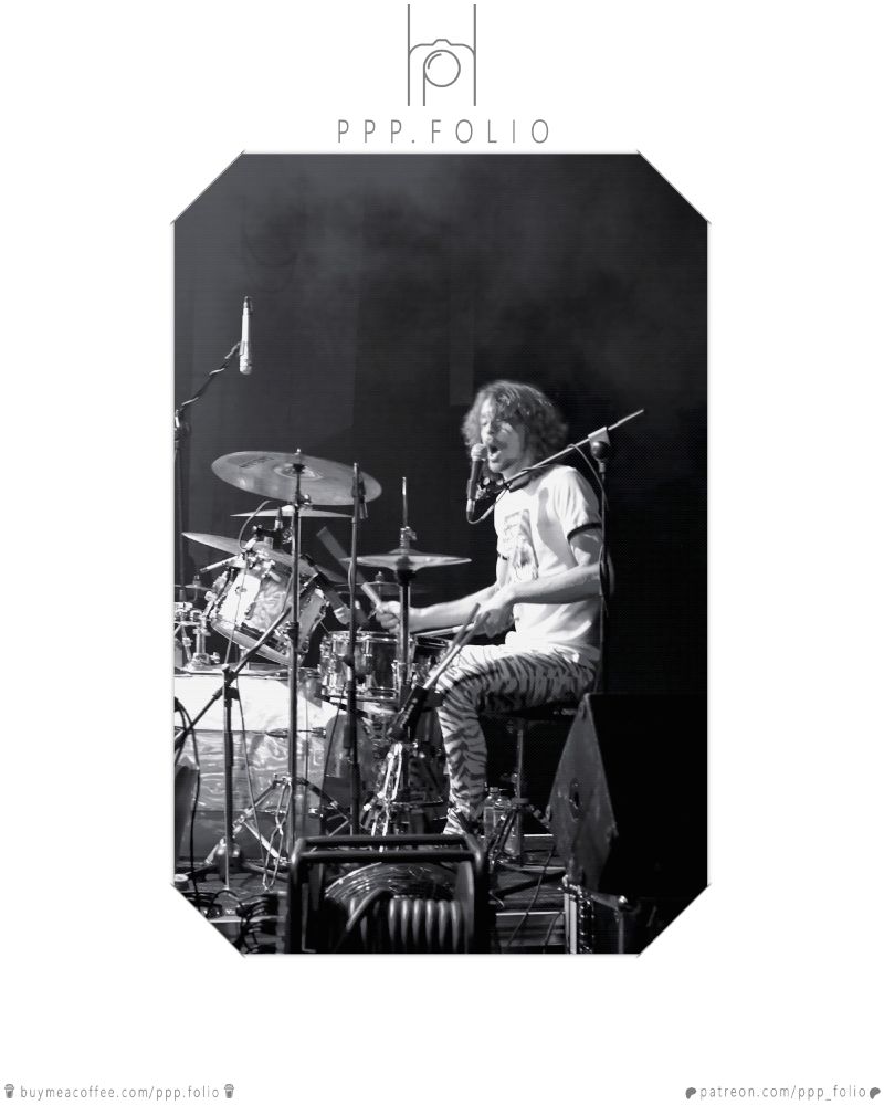 black and white image of a drummer at a concert taken from the side in the stage wings.