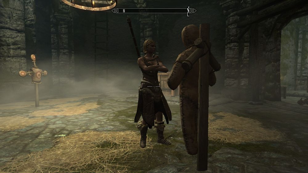 Captura de pantalla del juego TES V: Skyrim. Se ve a un bandido de pie con los brazos cruzados. Está enfrente de un muñeco de entrenamiento,  a apenas 3 metros del jugador