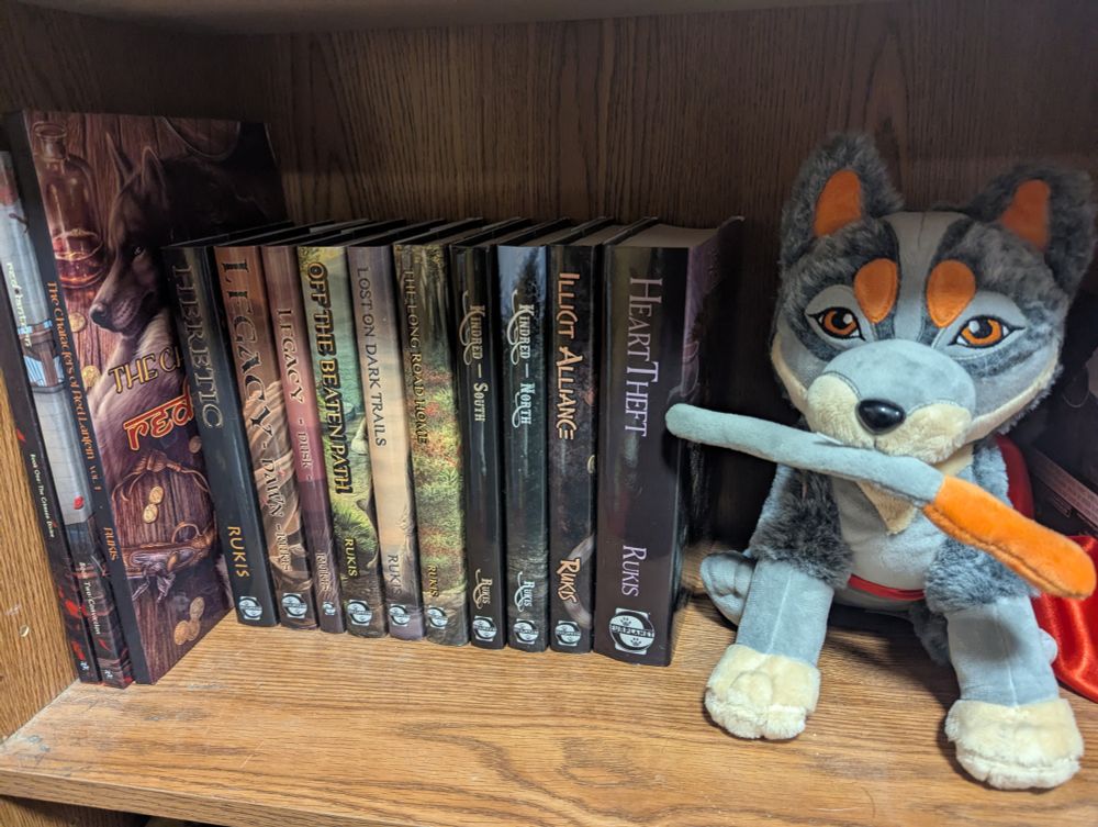 A plush cattle dog next to a hardcover book collection 