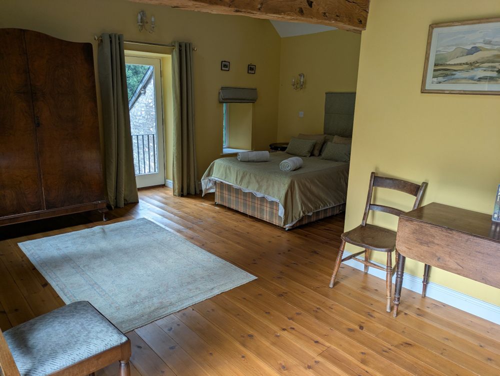 Another big bed room with wooden floors and furniture, beams over the ceiling