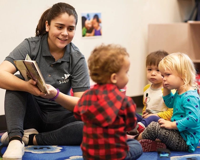 A childcare provider cares for three young children in a daycare center.