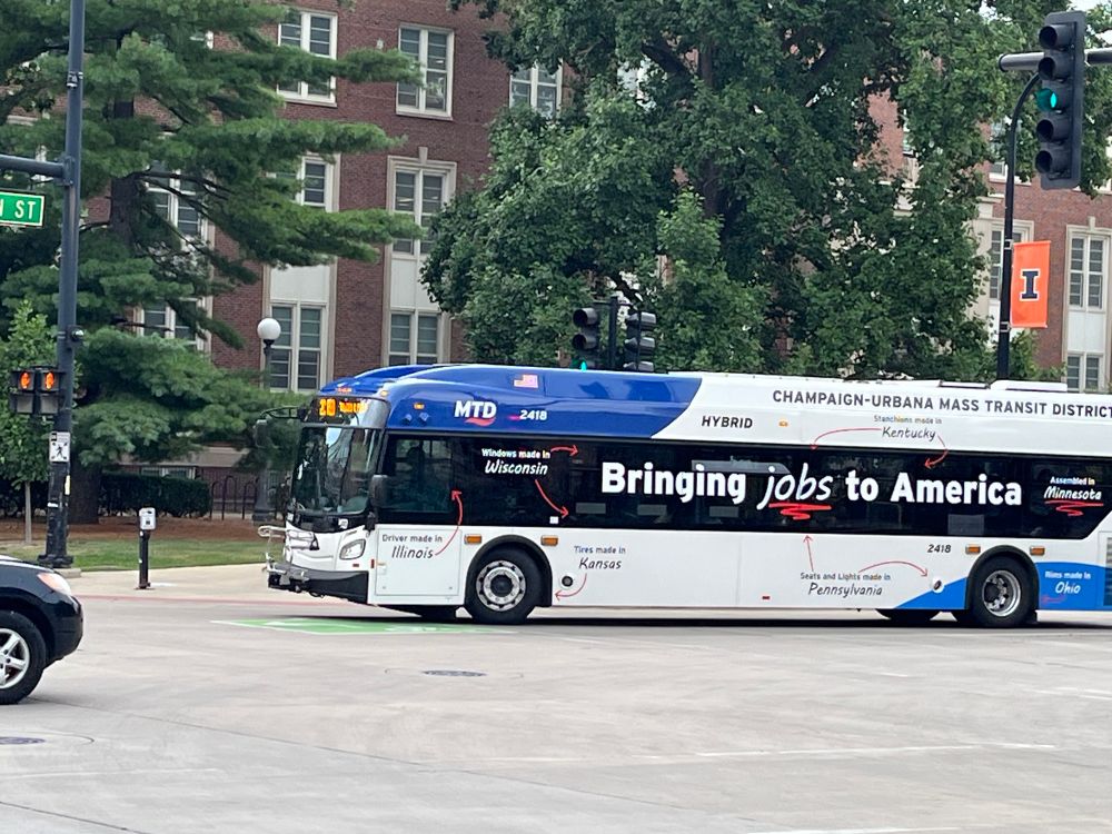 A city bus with “Bringing jobs to America” on the side. Arrows point to the various components of the bus, identifying them and the states in which they are made.