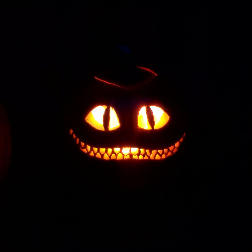 pumpkin with the cheshire cat's eyes and grin carved into it.