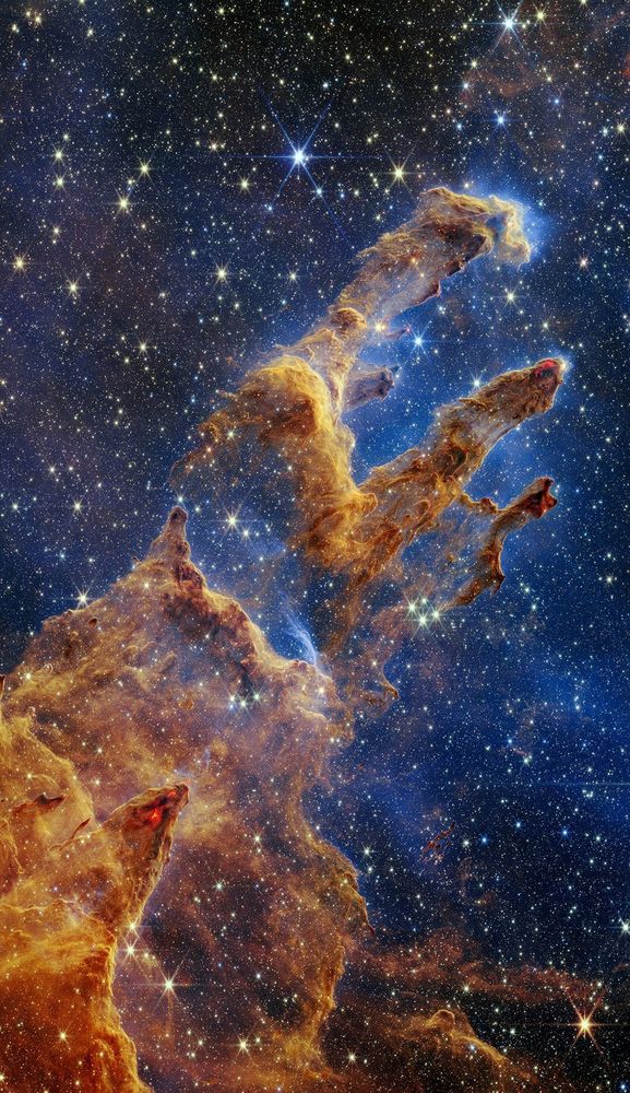 The Pillars of Creation are set off in a kaleidoscope of color in NASA’s James Webb Space Telescope’s near-infrared-light view. The pillars look like arches and spires rising out of a desert landscape, but are filled with semi-transparent gas and dust, and ever changing. This is a region where young stars are forming – or have barely burst from their dusty cocoons as they continue to form.

Newly formed stars are the scene-stealers in this Near-Infrared Camera (NIRCam) image. These are the bright red orbs that sometimes appear with eight diffraction spikes. When knots with sufficient mass form within the pillars, they begin to collapse under their own gravity, slowly heat up, and eventually begin shining brightly.