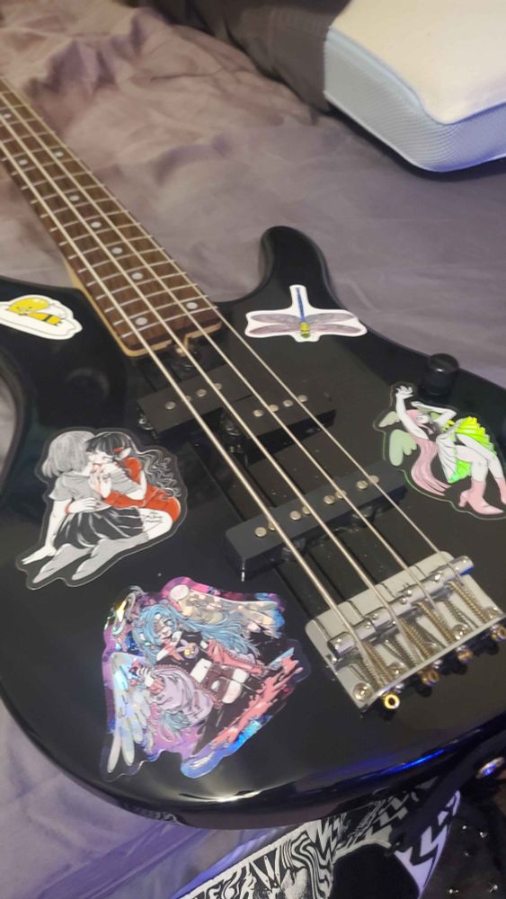 Front side of a bass guitar with stickers.