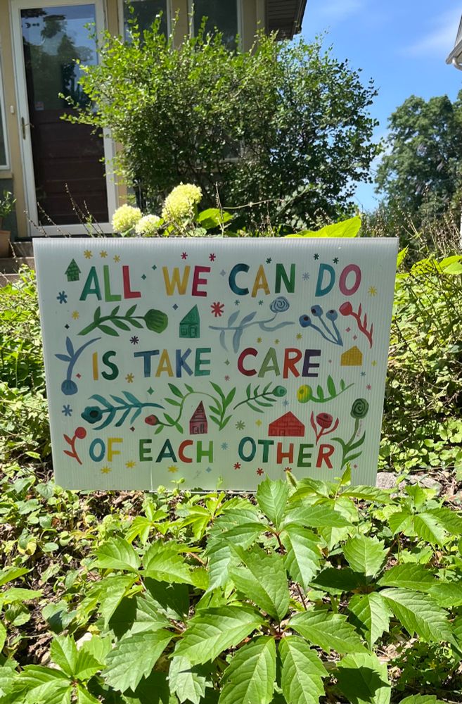 A colorful lawn sign reads “All we can do is take care of each other.”