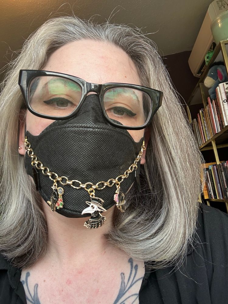 Stella wearing a mask and mask chain featuring a plague doctor. 