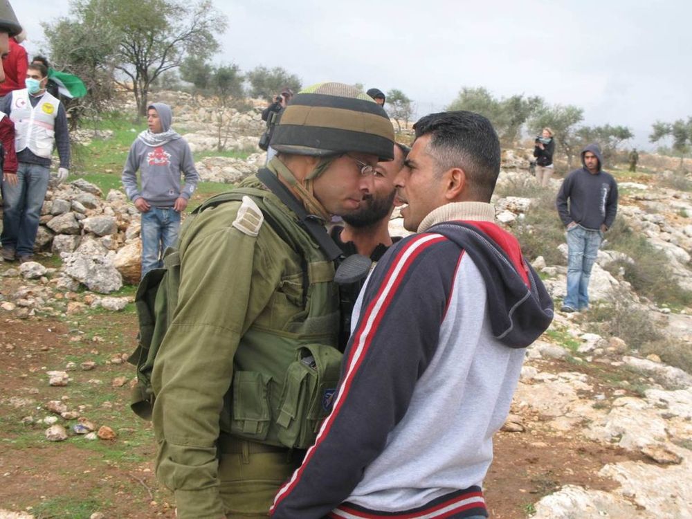 Unarmed peace activist Iyad Burnat standing nearly fore head to forehead in a confrontation with a fully armed IDF soldier