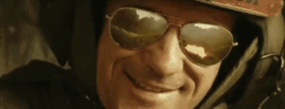 a man wearing sunglasses and a helmet is smiling