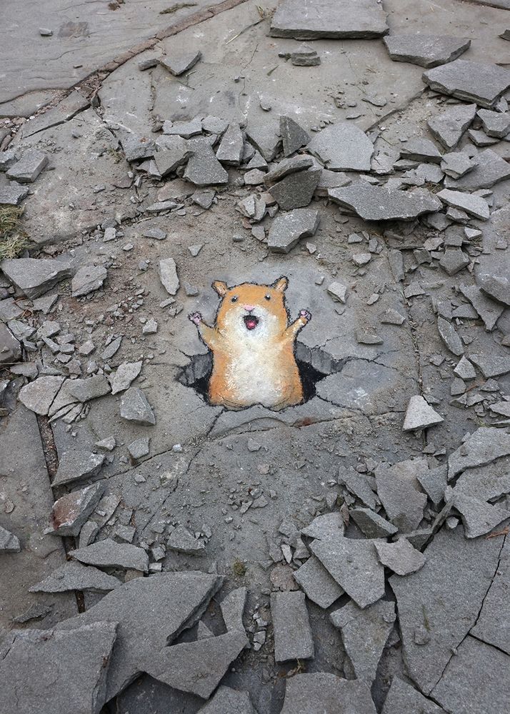 sidewalk chalk drawing of a hamster breaking victoriously through a hole in a flagstone walkway, surrounded by rubble