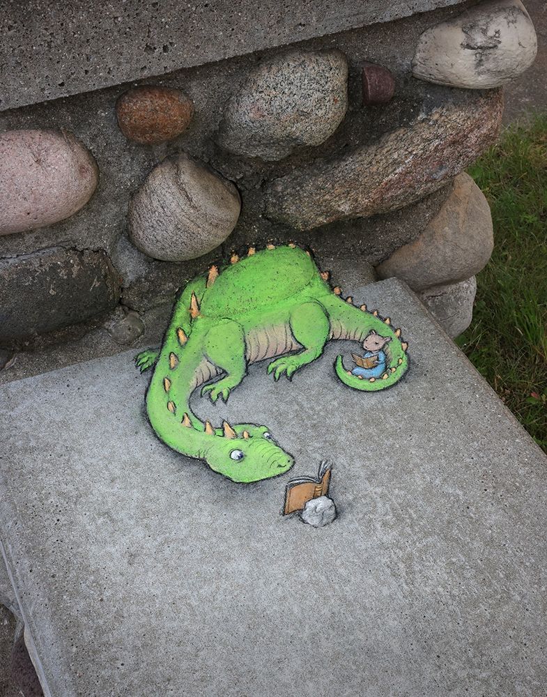 sidewalk chalk drawing of a mouse reading a book while sitting in the curl of the tail of a dinosaur who is also reading a book