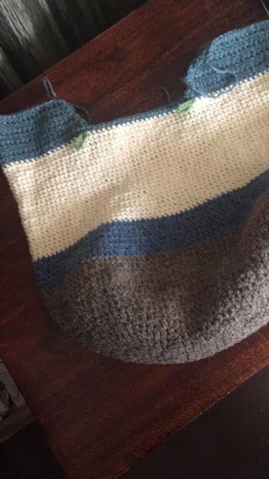 Crochet bag for future projects sits on a wooden bench. 