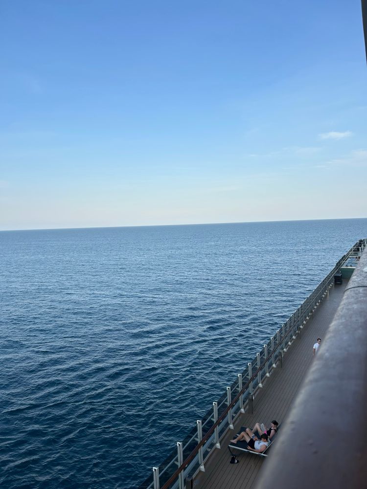A view of open ocean water, dark blue, with the deck of a cruise ship visible on the right.