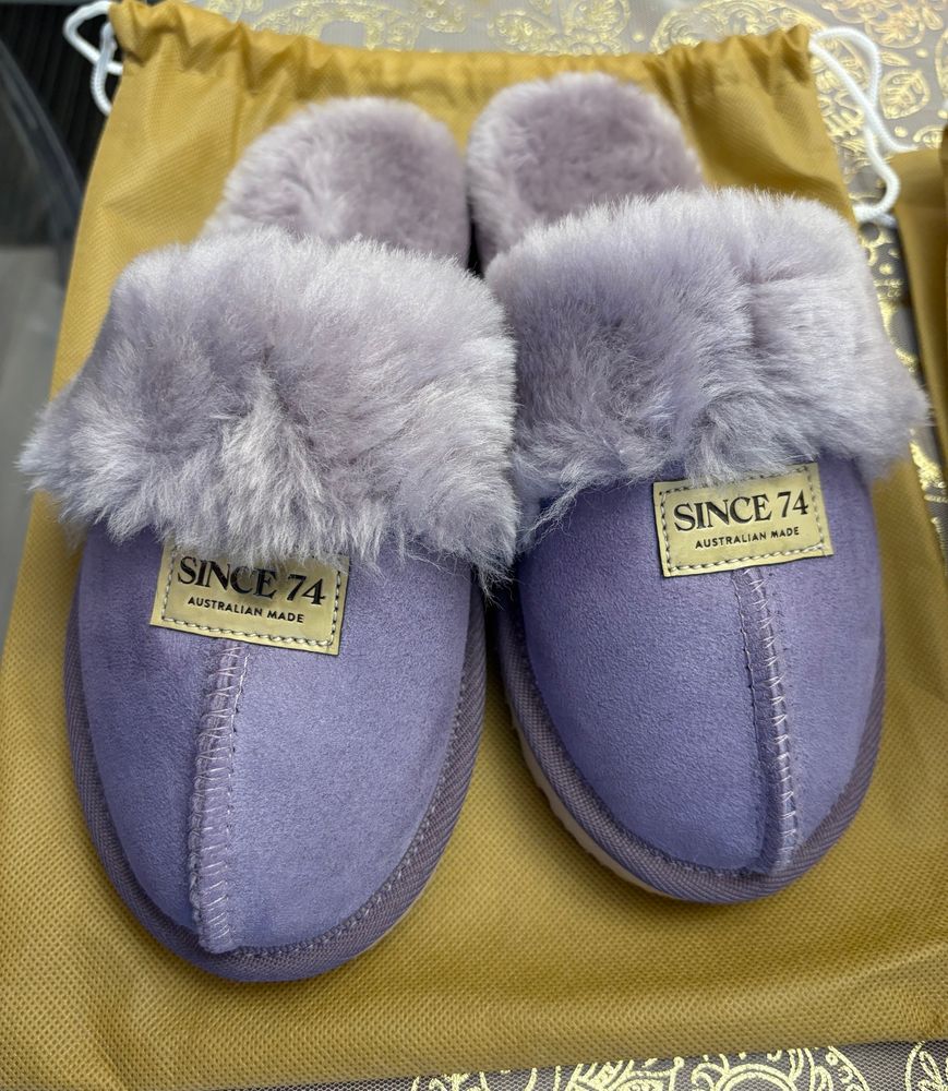 A pair of purple UGG slippers on top of mustard cloth. 