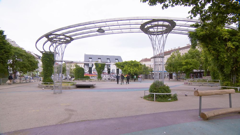 Der Yppenplatz, ein Metallgerüst mit einzelnen Grünpflanzen rund um einen versiegelten Platz