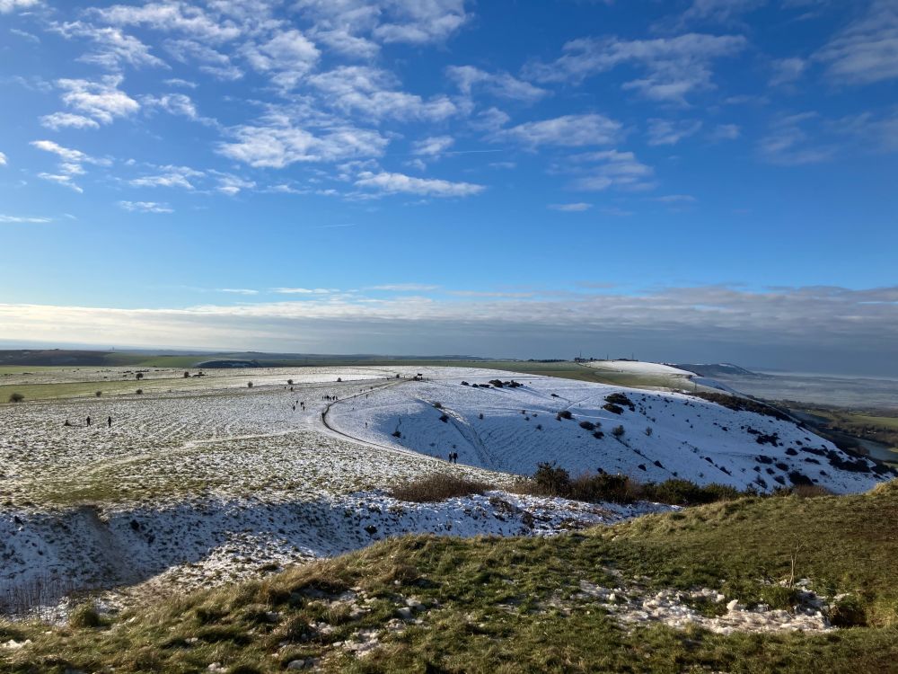 The Sussex downs only half covered in snow with a very blue sky behind 