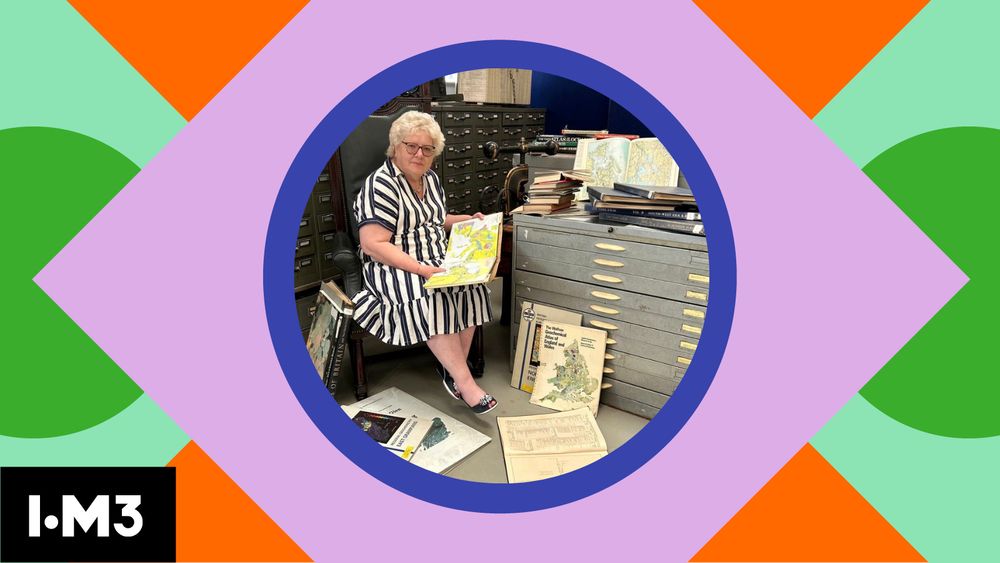 IOM3 President, Christine Blackmore sits in an archive room surrounded by drawers and stacks of vintage maps. She’s holding an open map and smiling at the camera. The image is framed in a colourful, geometric design with the IOM3 in the bottom left corner. This photo is taken at the IOM3 library.