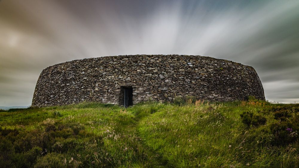A long exposure shot of the only entrance of an ancient ring fort in Ireland. The clouds streak across the sky giving a smooth but epic look and feel to the course, unmovable rocks that make up the barrier wall of this fort. Stairs run up and down the sides of this fort to access the ramparts, where ferns grow down the sides. A long exposure shot of the only entrance of an ancient ring fort in Ireland. The clouds streak across the sky giving a smooth but epic look and feel to the course, unmovable rocks that make up the barrier wall of this fort. 