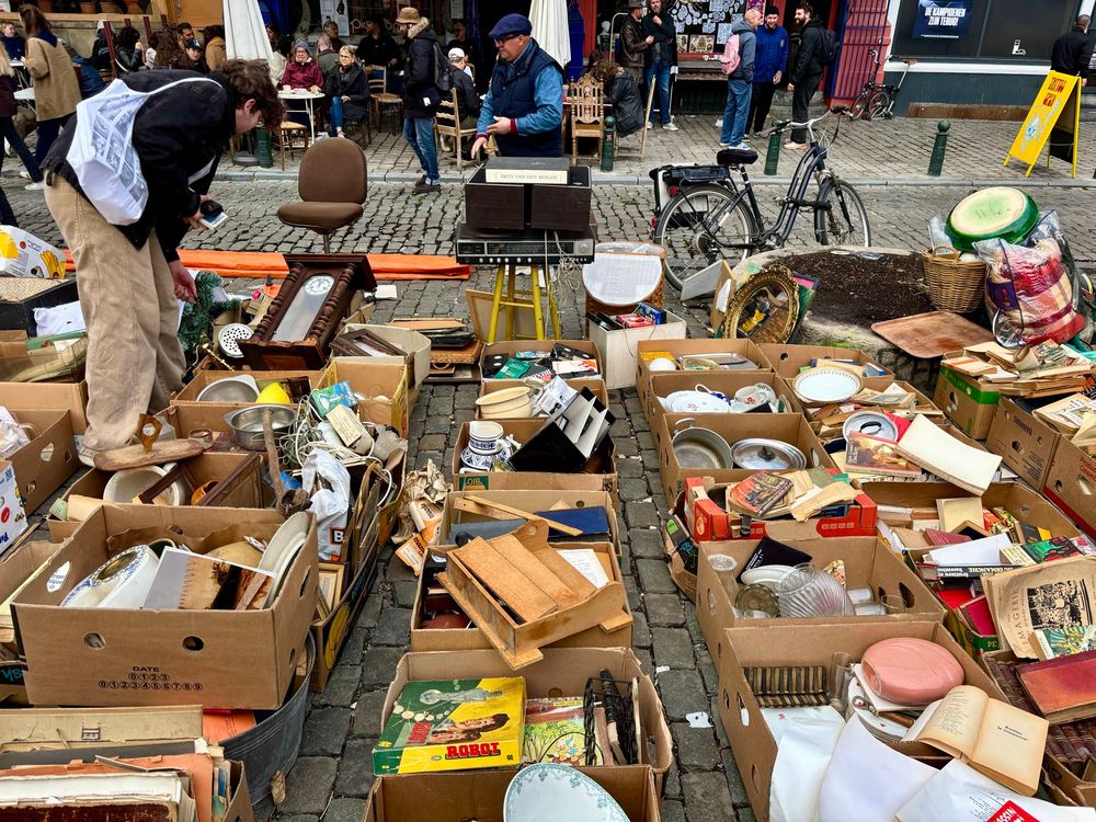 Scene at Brussels flea market. Tonnes of cardboard boxes filled with junk on cobblestones. 